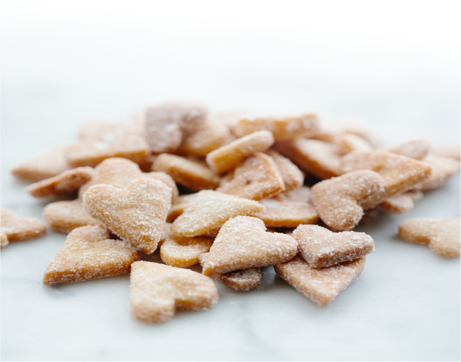 a pile of small, heart-shaped shortbread cookies on a white marble table